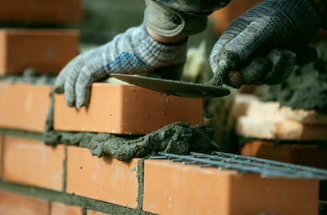 Fresh course of brick going down on full mortar beds
